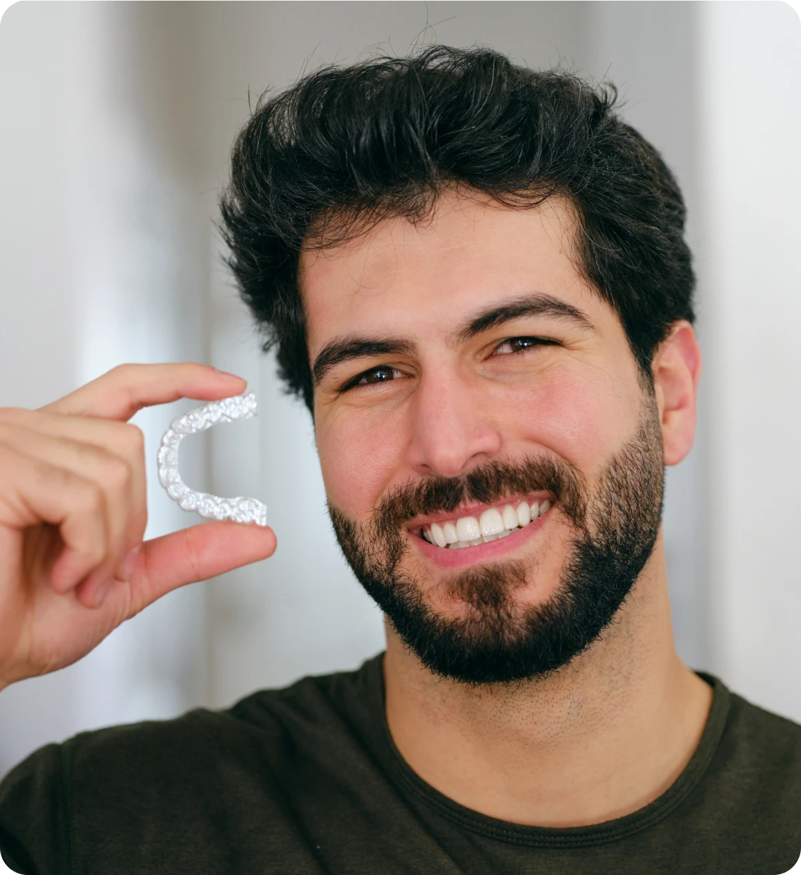 Man holding a dental aligner, smiling